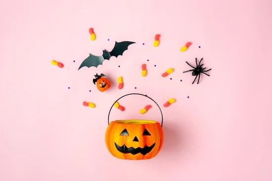 Một xô bí ngô làm đổ kẹo halloween và đồ chơi ma quái